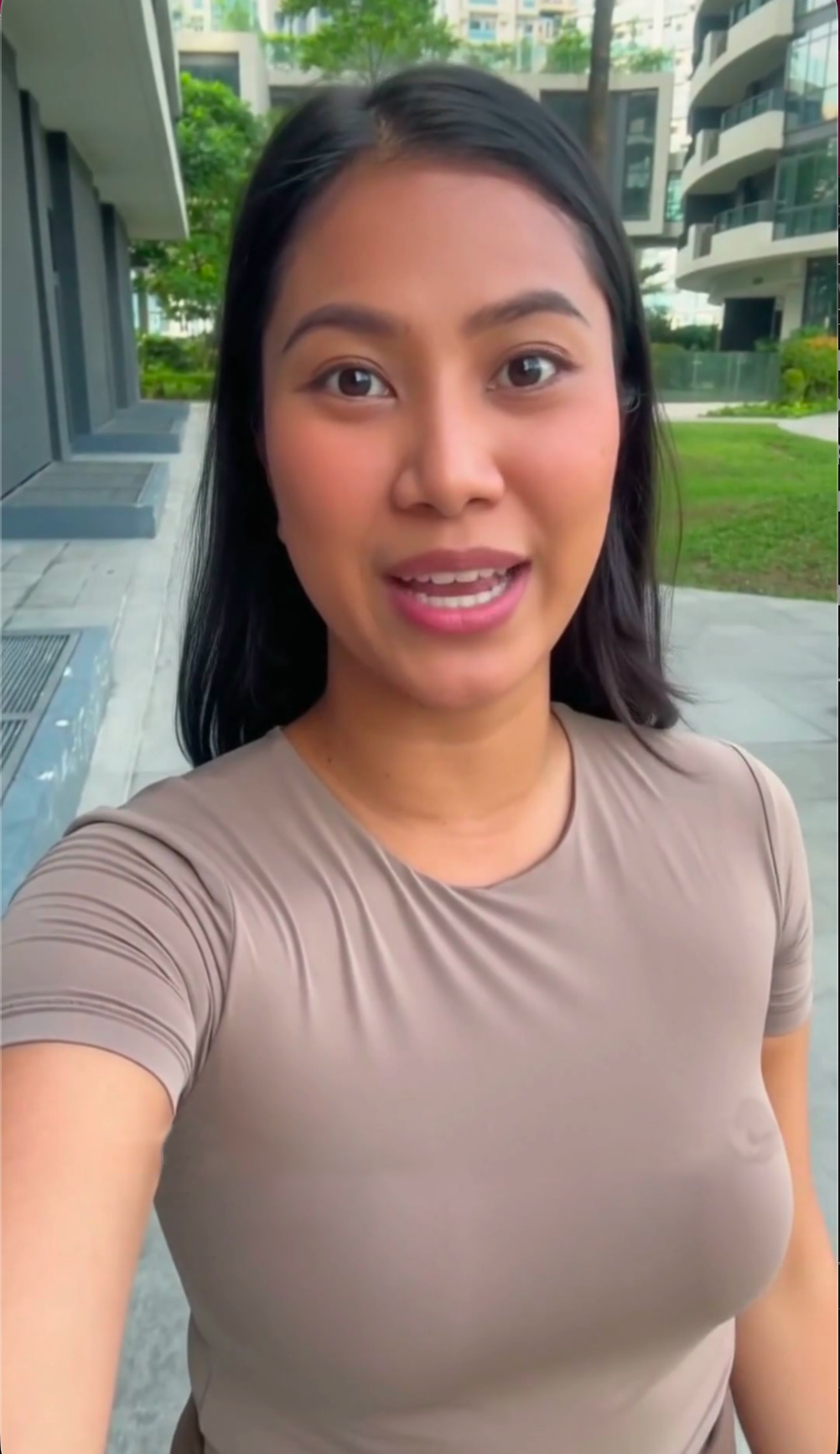 Presenter speaking outdoors beside a landscaped residential property
